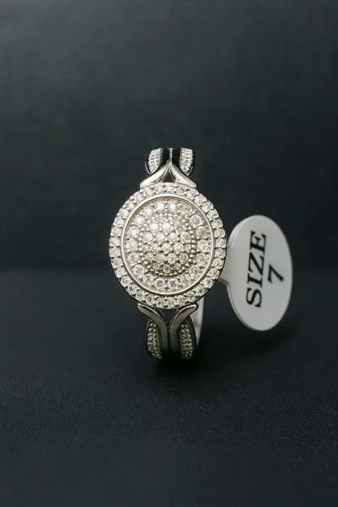 Silver ring with a large circular setting featuring multiple small American diamonds