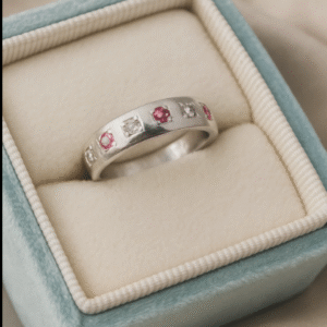 sterling silver band ring with alternating ruby and diamond accents, displayed in a soft blue velvet ring