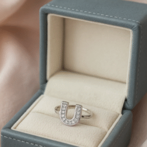 silver U-shaped initial ring with zircon stones, displayed in a luxury grey velvet jewellery box on satin fabric.