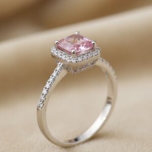 925 silver ring with pink square-cut stone and diamond halo on a beige background.